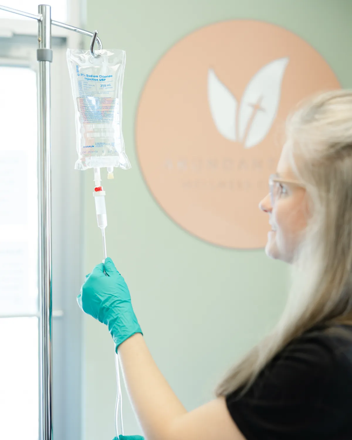 A nurse hanging an IV bag on the pole in the IV room
